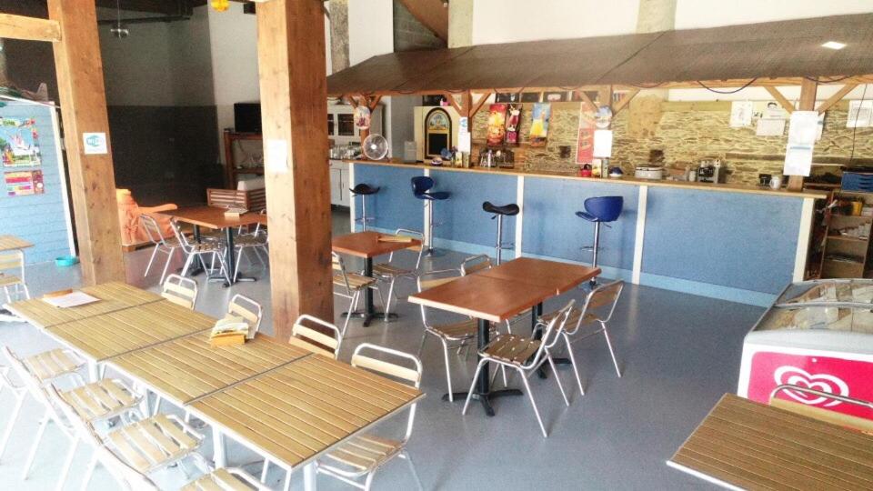 un restaurant avec des tables et des chaises ainsi qu&#39;un bar dans l&#39;établissement Camping le Village de Florine, à Coëx