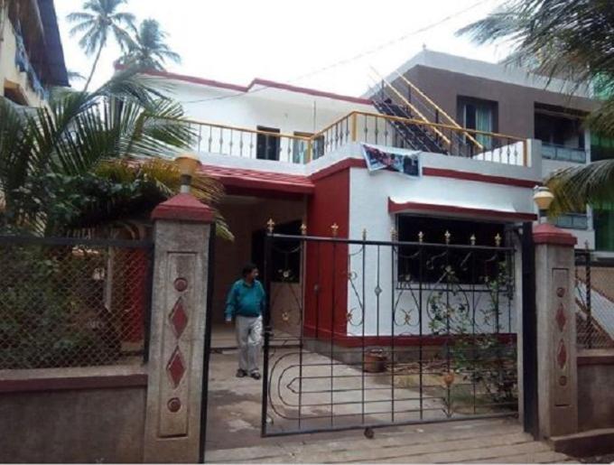 a man standing in front of a house with a gate at NILESH COTTAGE in Alibaug