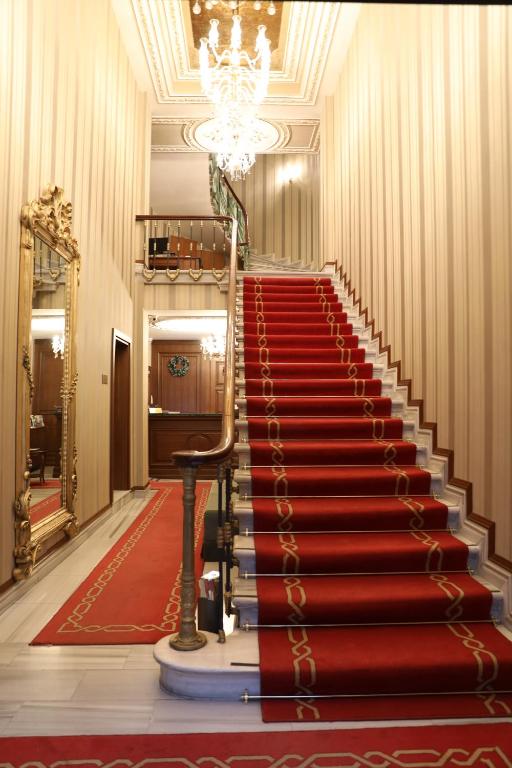 eine rote Teppichtreppe in einem Gebäude mit einem Kronleuchter in der Unterkunft Meserret Palace Hotel - Special Category in Istanbul