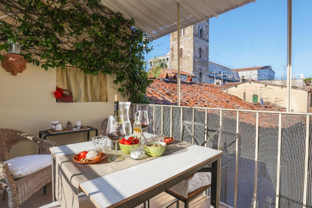una mesa con comida y copas de vino en el balcón en Terrazza San Martino, en Lucca