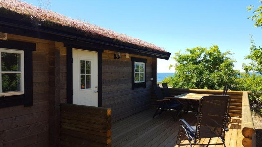 ein Haus mit einer Terrasse mit einem Tisch und Stühlen in der Unterkunft Sjötorpet - unikt boende vid havet på norra Öland! in Löttorp