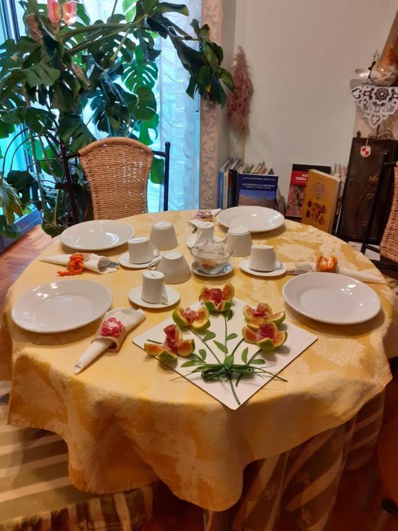 una mesa con platos blancos y flores en ella en B&B Stupor Mundi, en Altamura