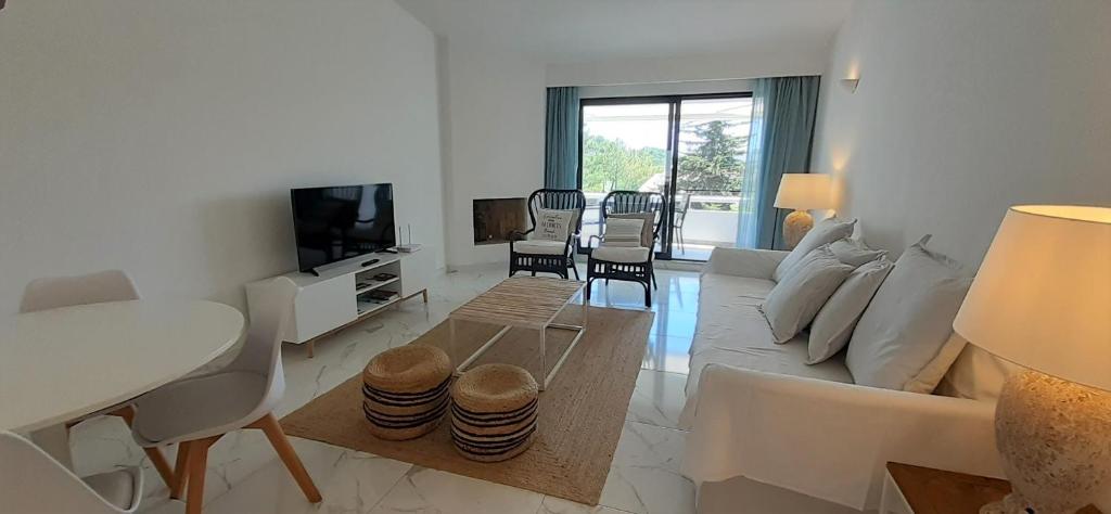a white living room with a couch and a tv at Quinta do Lago Beach House in Quinta do Lago