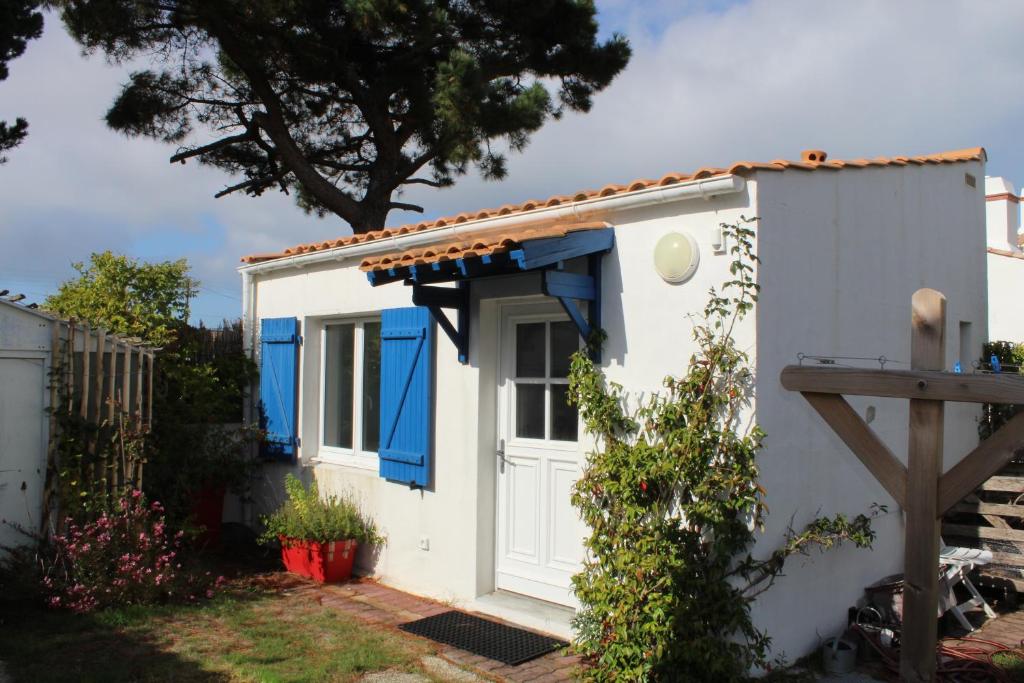 uma pequena casa com uma porta azul e uma árvore em Petit studio CYPRÈS du BOIS em Noirmoutier-en-l'lle