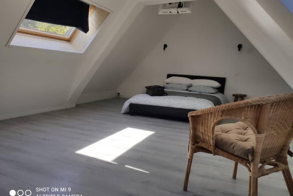 a attic bedroom with two beds and a chair at brelevenez 18 rue crec h quellien in Lannion