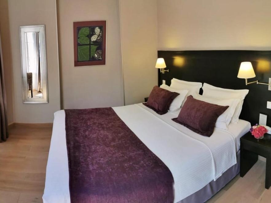 a bedroom with a large white bed with purple sheets at La Place Boutique Hotel in Antibes