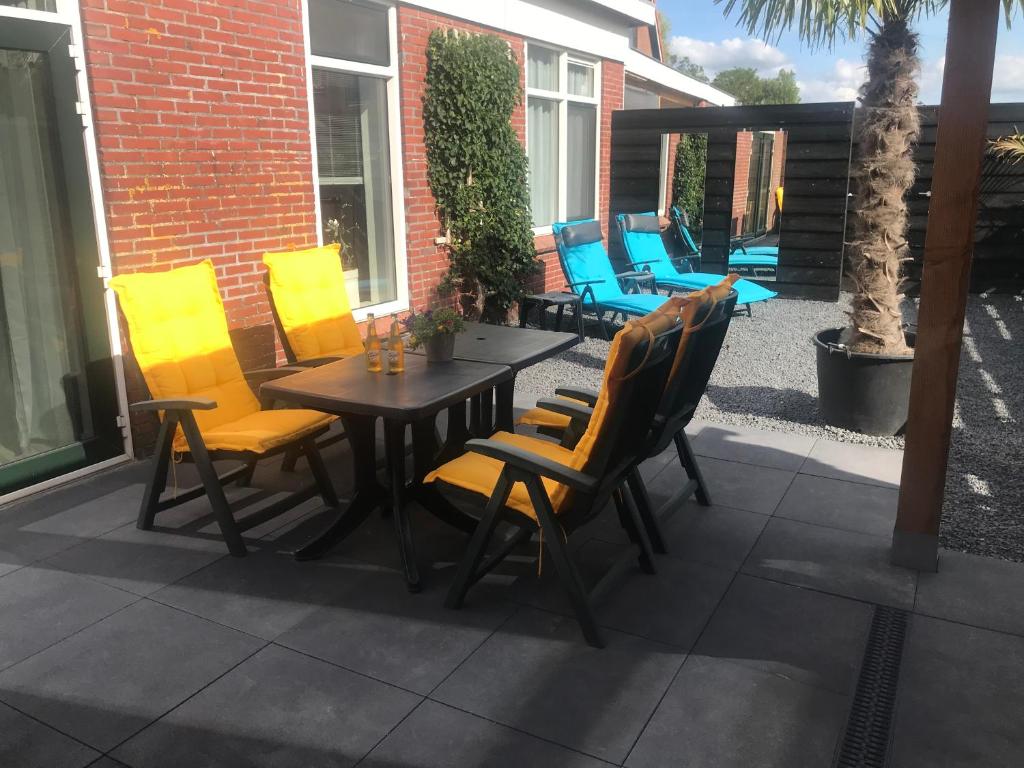 um pátio com cadeiras amarelas e uma mesa de madeira em Vakantie aan de Lauwers em Gerkesklooster