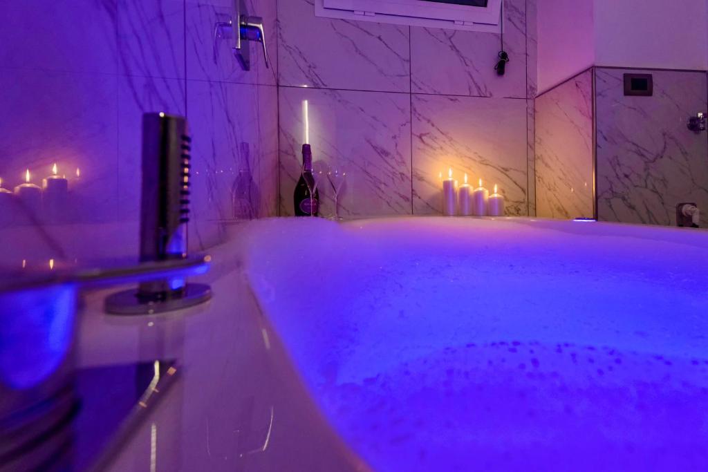een badkamer met een bad met paarse verlichting en kaarsen bij Sara luxury apartament 2 in Sorrento