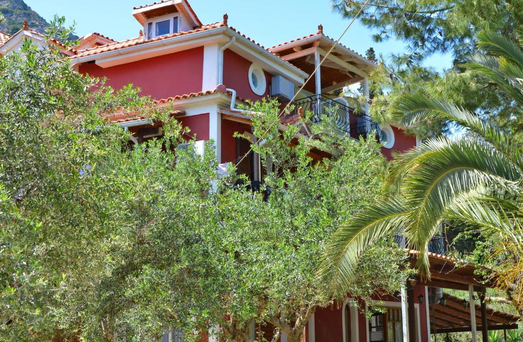 una casa roja con árboles delante de ella en Belvedere Zakynthos Studios, en Vasilikos