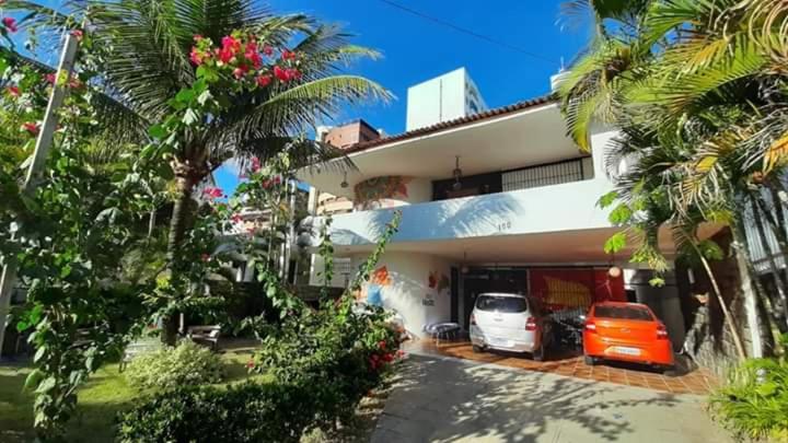 a house with two cars parked in front of it at Regiane Beach Pousada Hostel in João Pessoa