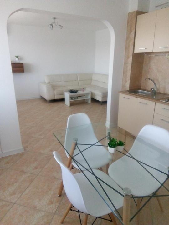 a living room with a glass table and white chairs at Apartament bell confort in Tulcea
