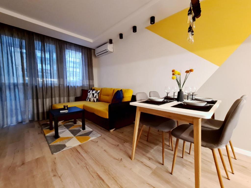 a living room with a table and a yellow couch at Modern and cozy flat in the city center in Varna City