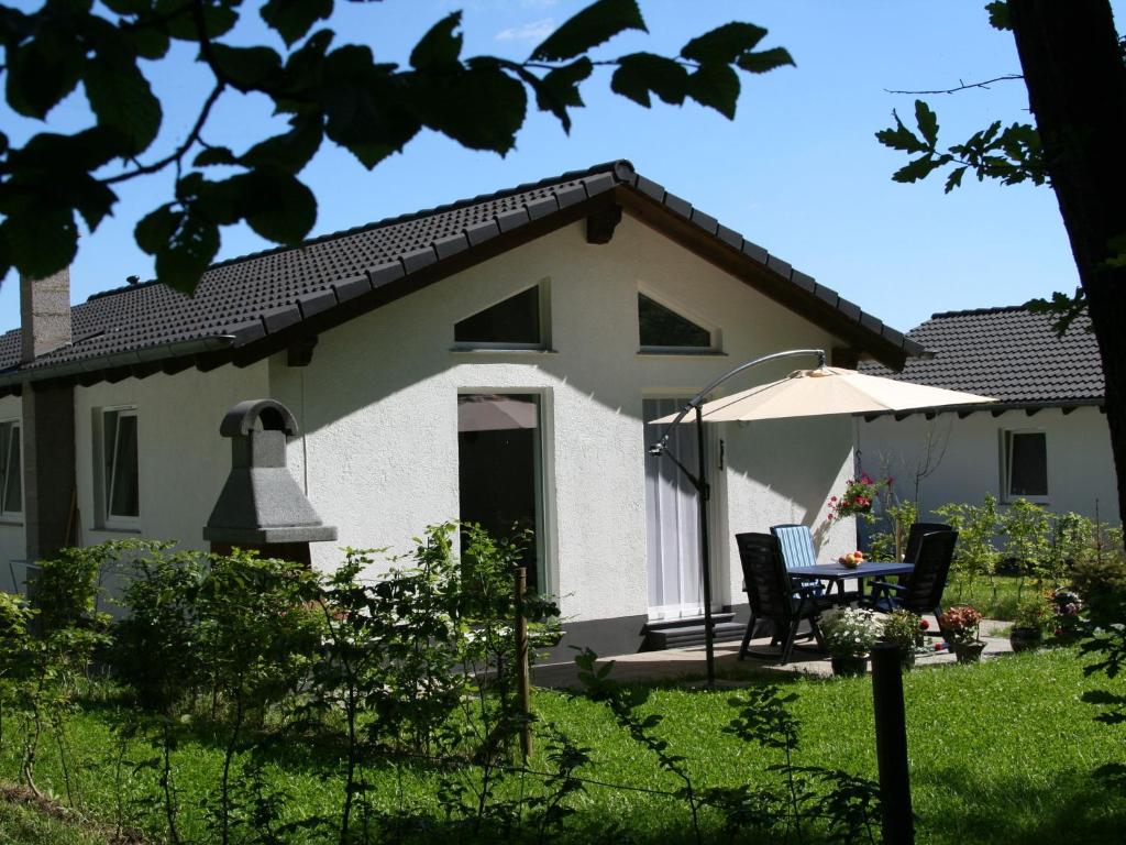 ein weißes Haus mit einem Tisch und einem Regenschirm in der Unterkunft Tidy holiday home with dishwasher, in a green area in Kopp