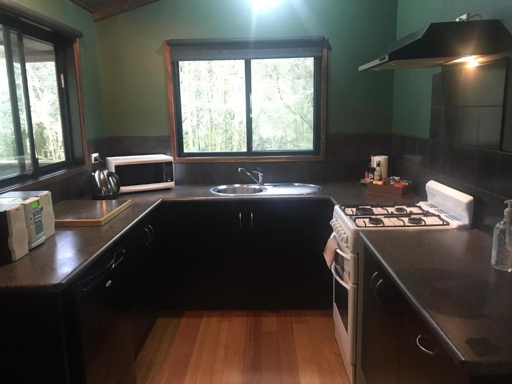 a kitchen with a sink and a stove top oven at parkwood cottage in Lavers Hill