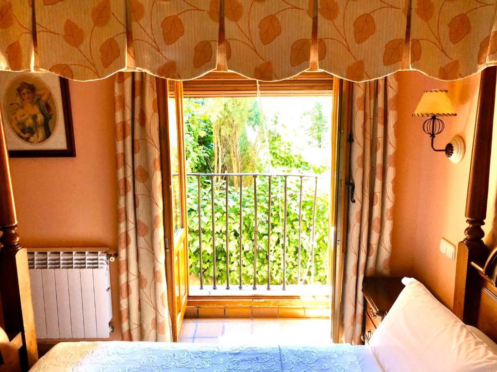 a bedroom with a bed and a window with a balcony at Hostal Posada La Panadera in Sepúlveda