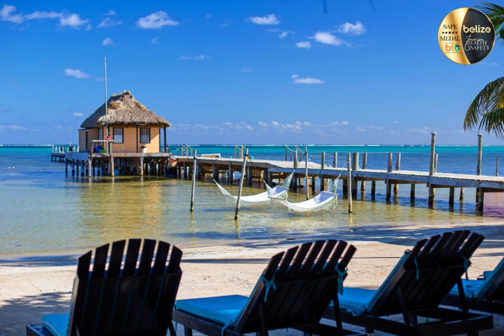 two chairs and a hammock on a beach with a dock at Portofino Beach Resort-An Authentic Island Escape! in San Pedro