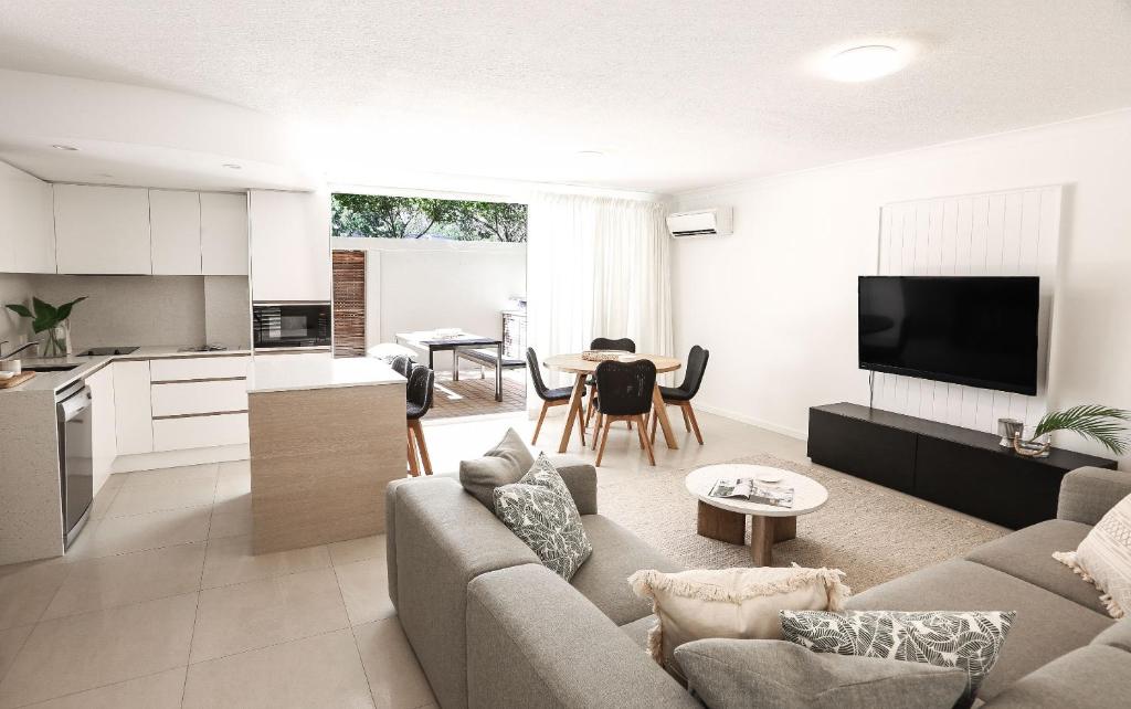 a living room with a couch and a kitchen with a table at Portofino 2 in Noosa Heads