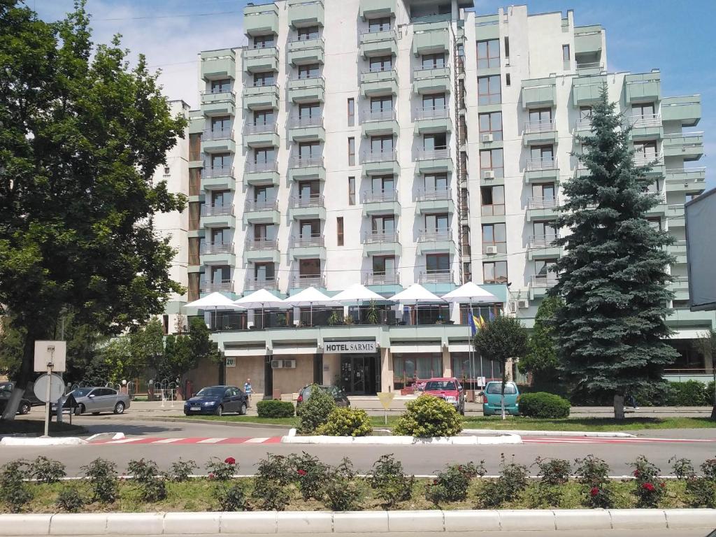 un grand bâtiment blanc avec un arbre en face dans l'établissement Hotel Sarmis, à Deva