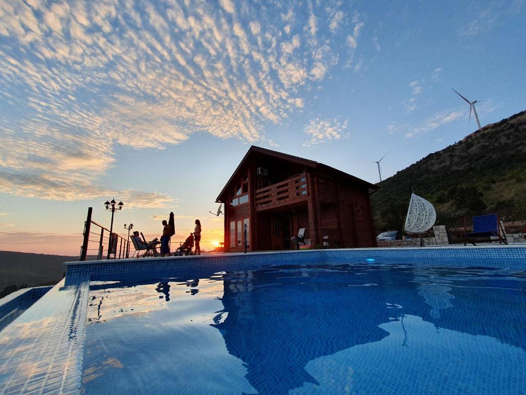 - un coucher de soleil sur une piscine en face d'une maison dans l'établissement Katune 2020, à Kruta