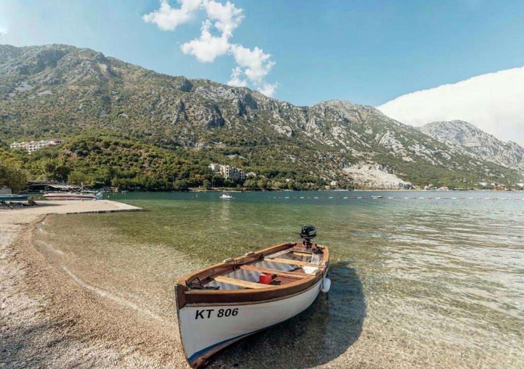 łódź siedząca na brzegu plaży w obiekcie Bobana Apartments w mieście Donji Morinj
