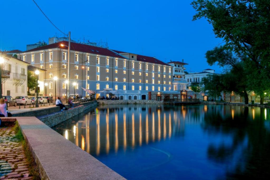 ein Gebäude, das nachts neben einem Fluss liegt in der Unterkunft Hydrama Grand Hotel in Drama