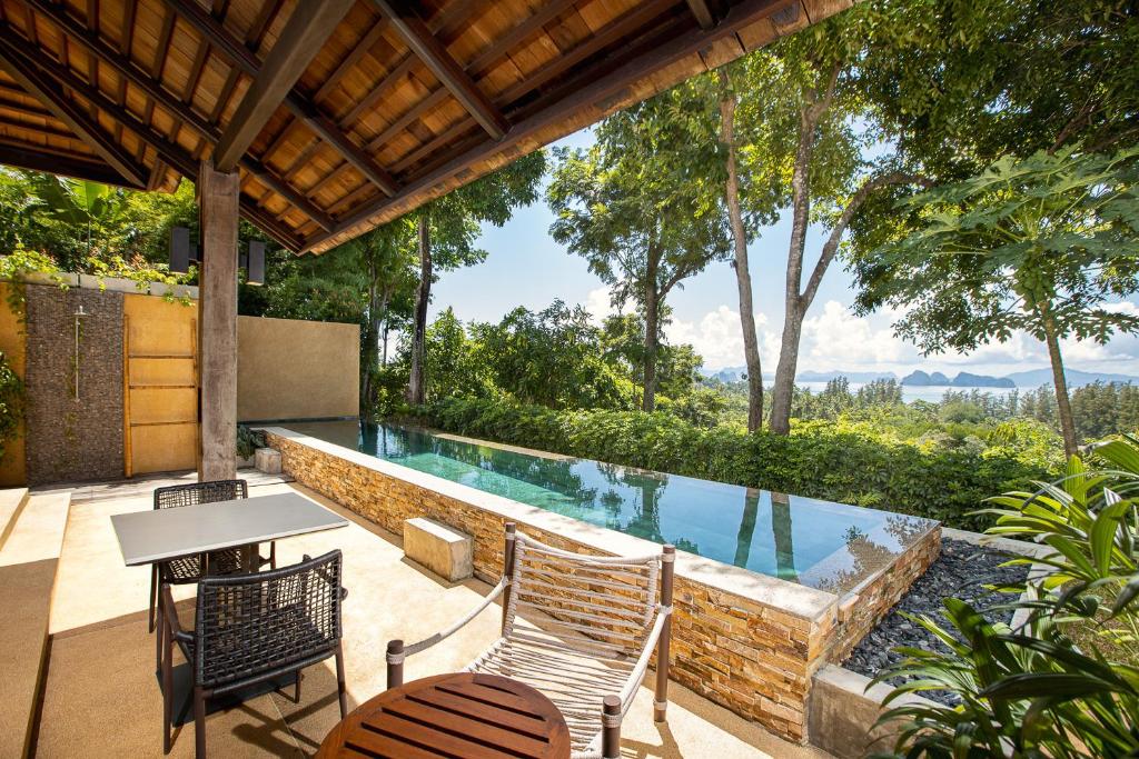 a swimming pool with chairs and a table on a patio at SAMSAM Yao Noi - ANDAMAN MAGIC & ART VILLAS in Ko Yao Noi
