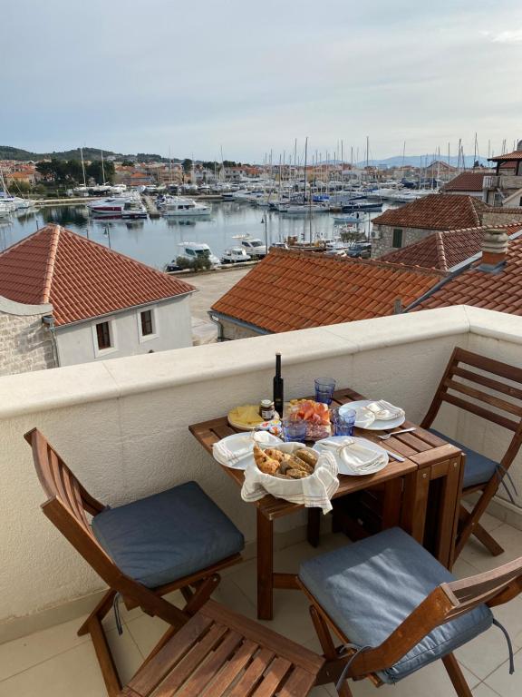 a table with food on a balcony with a view of a harbor at Tribunj House in Tribunj