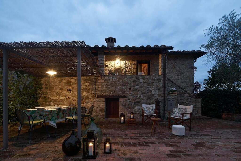 eine Terrasse mit Tisch und Stühlen und ein Gebäude in der Unterkunft Premiere Apartments - Residenza Le Rose nel Chianti in Lornano