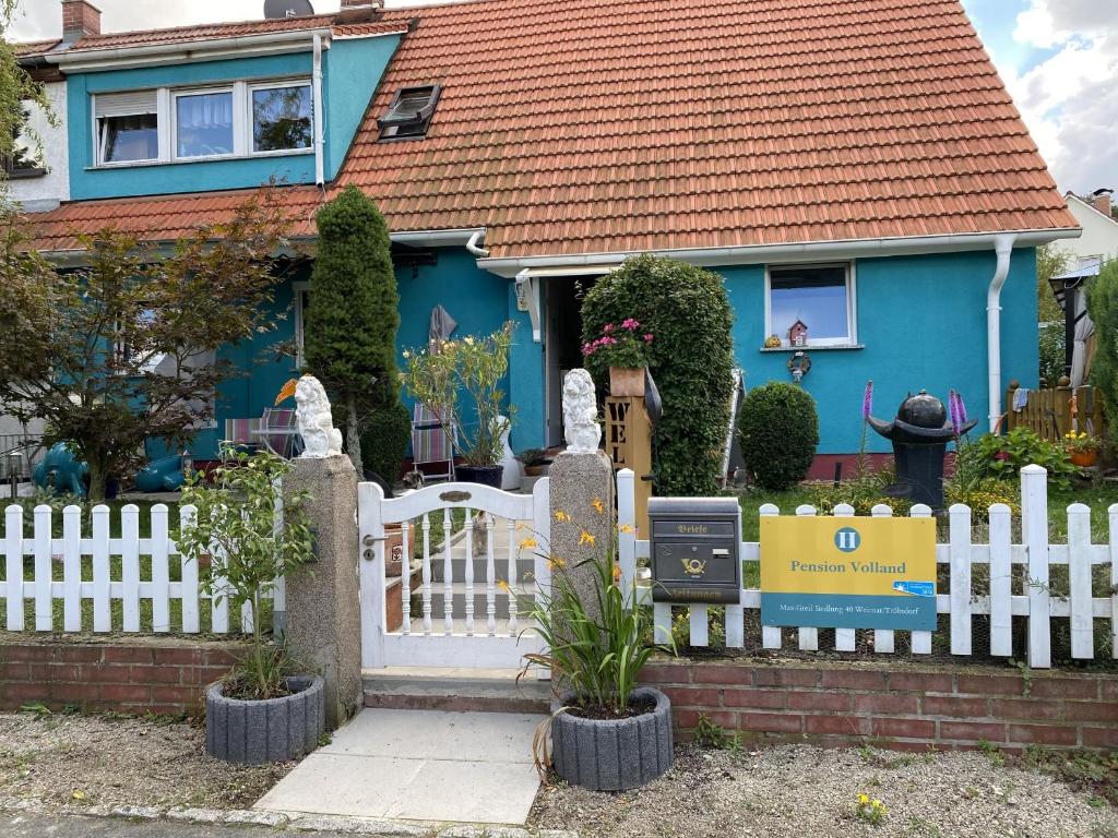 ein Haus mit einem weißen Zaun und einem blauen Haus in der Unterkunft Zimmervermietung Volland in Weimar