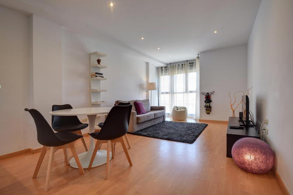 sala de estar con mesa, sillas y sofá en Malvarrosa Beach Apartment, en Valencia