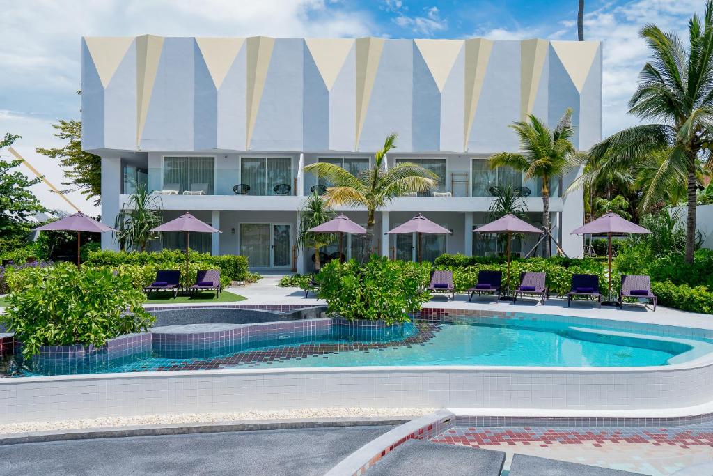 a resort with a pool and chairs and a building at La Vida Samui in Chaweng