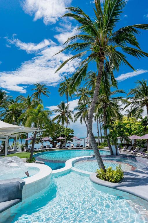 a swimming pool with palm trees in a resort at La Vida Samui in Chaweng