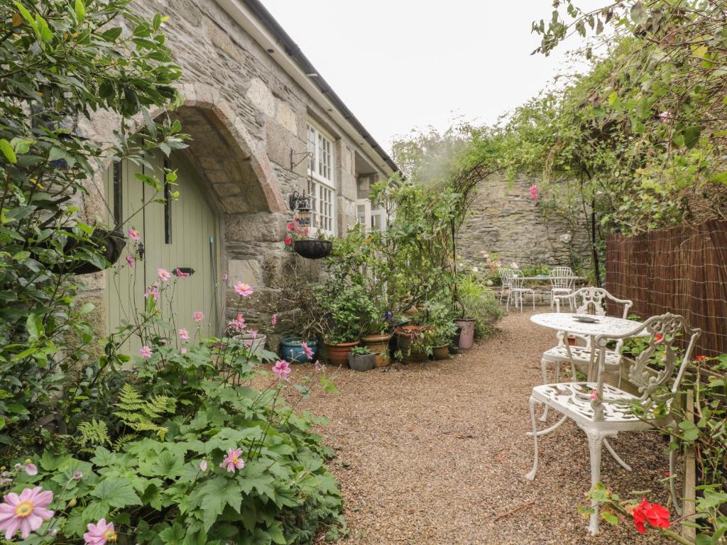 een tuin met een tafel, stoelen en bloemen bij Coinage Hall in Lostwithiel