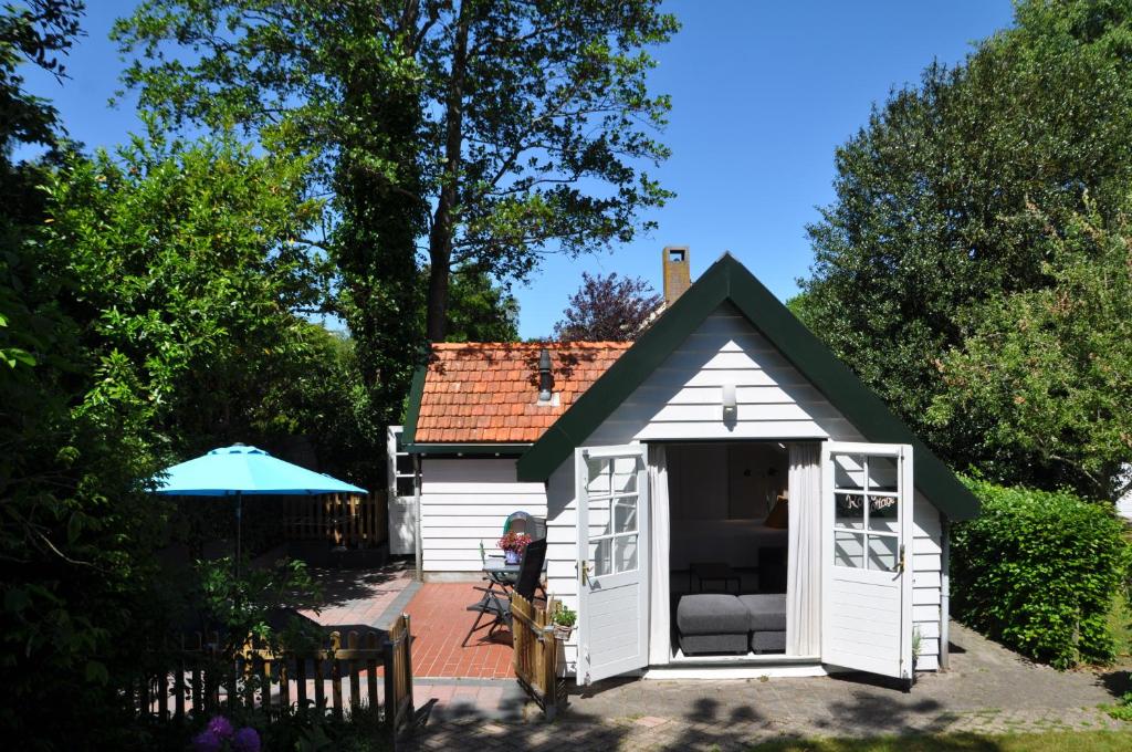 um pequeno barracão branco com um telhado verde em Rob's Cottage em Schoorl