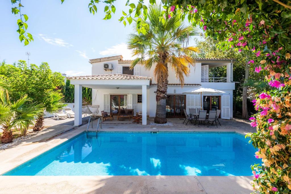 a villa with a swimming pool in front of a house at Villa Beach Palmitos in Can Picafort
