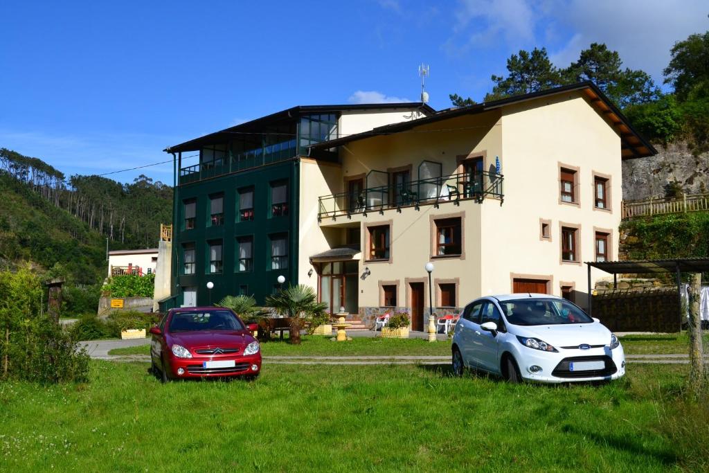 dois carros estacionados em frente a um edifício em Hotel Restaurante Canero em Canero