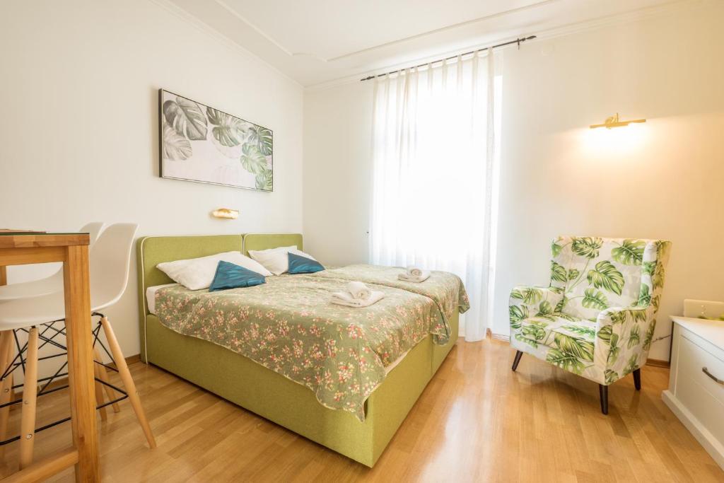 a small bedroom with a bed and a chair at Apartments Villa Devana 2 in Opatija