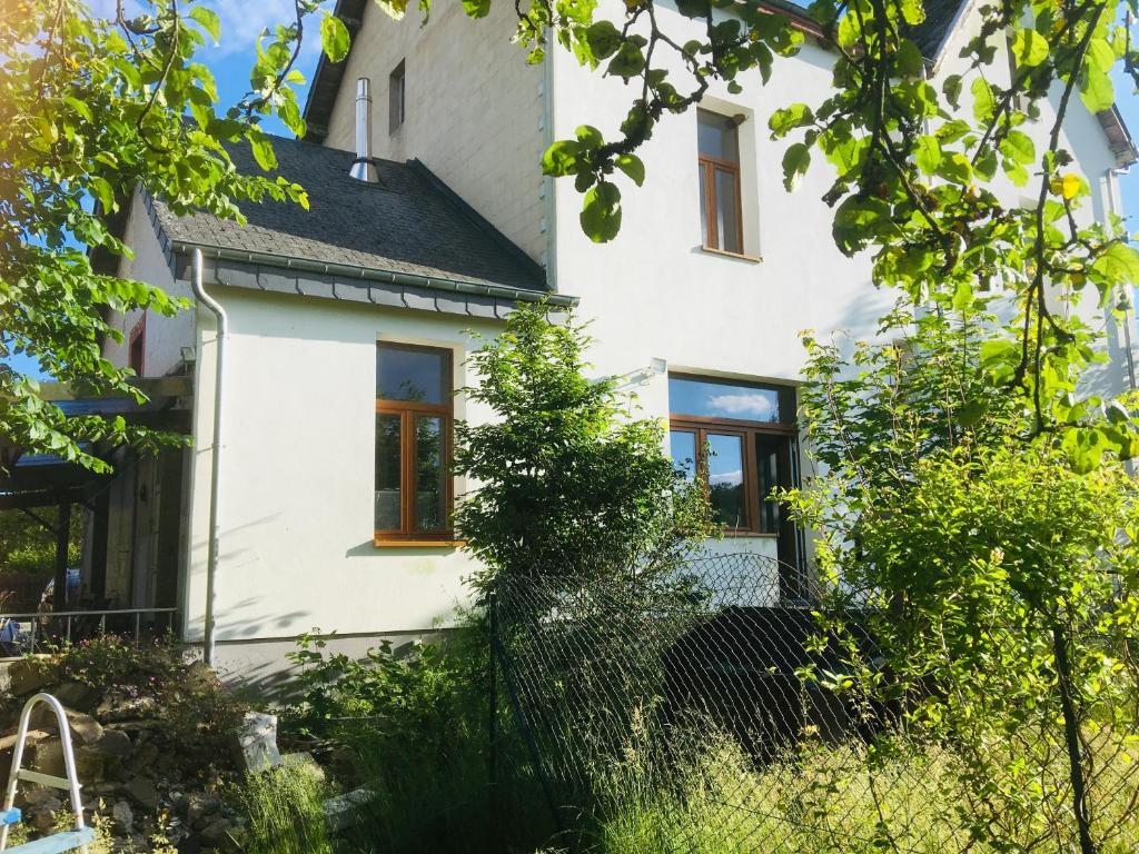 une maison blanche avec des arbres devant elle dans l'établissement Le nichoir d’hirondelles, à Tintigny