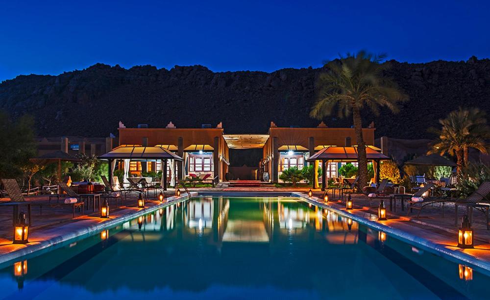 a swimming pool with lights in front of a house at HOTEL Bab Rimal in Foum Zguid