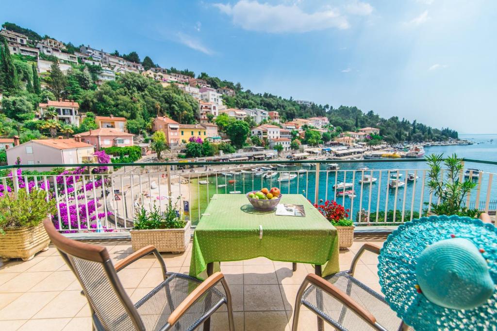 a table and chairs on a balcony with a view of the water at Room Mariza in Rabac