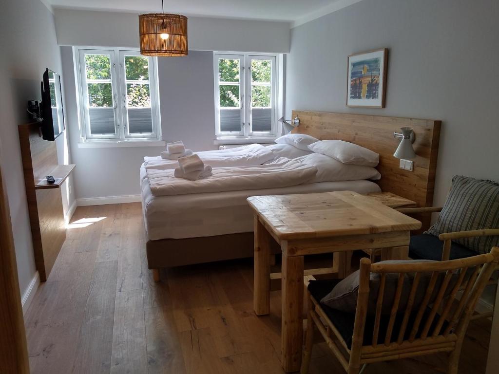 Schlafzimmer mit einem Bett, einem Tisch und Fenstern in der Unterkunft Tetens Gasthof in Süderlügum