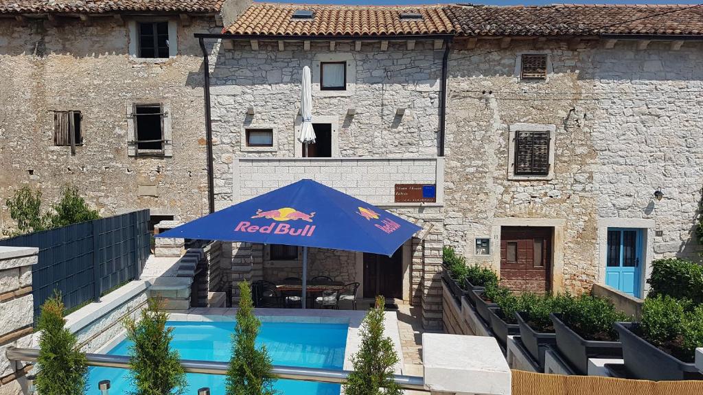 a red bull umbrella in front of a building at Stone House Istria HRIS 1 in Baderna