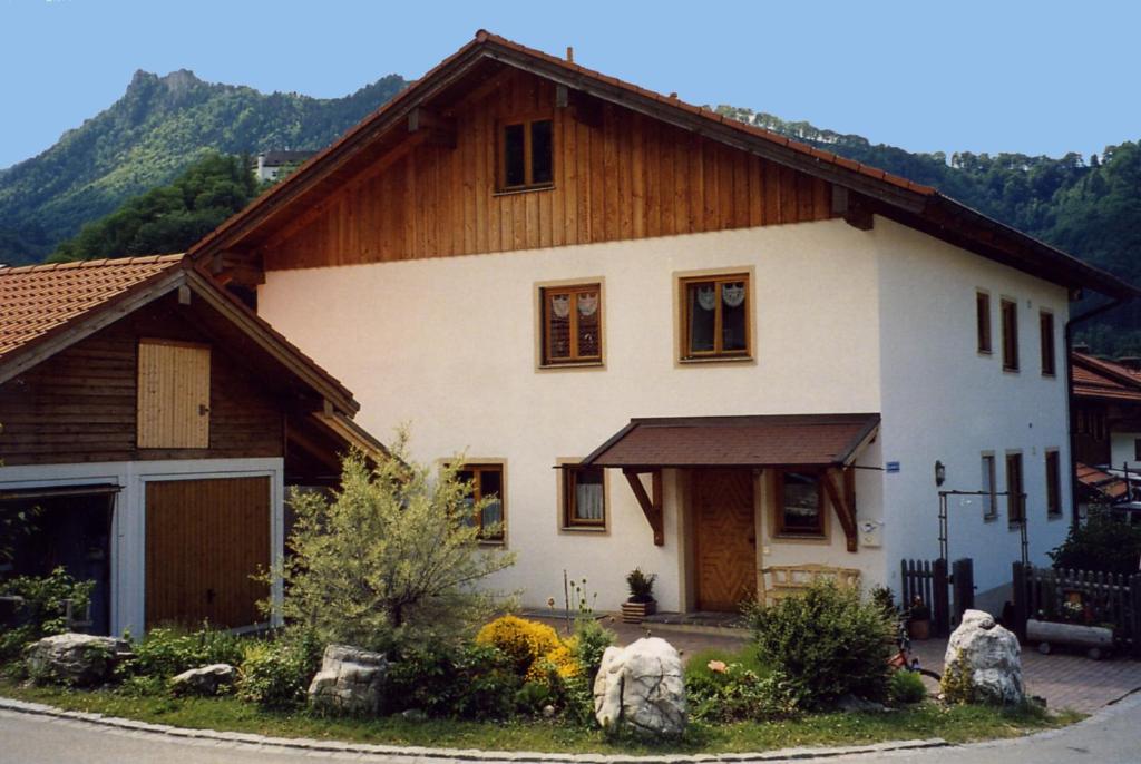 ein großes weißes Haus mit Holzdach in der Unterkunft Ferienwohnung Schwinghammer in Aschau im Chiemgau