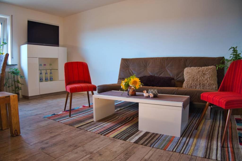sala de estar con sofá y 2 sillas rojas en Ferienwohnung-M8 im schönen Werratal en Jestädt