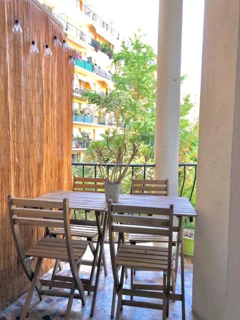 une table et des chaises en bois sur un balcon dans l'établissement Appartement NICE proche MER et CENTRE, à Nice