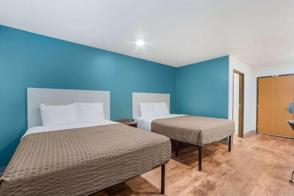 a room with two beds and a blue wall at WoodSpring Suites | North Charleston Airport I-526 in Charleston