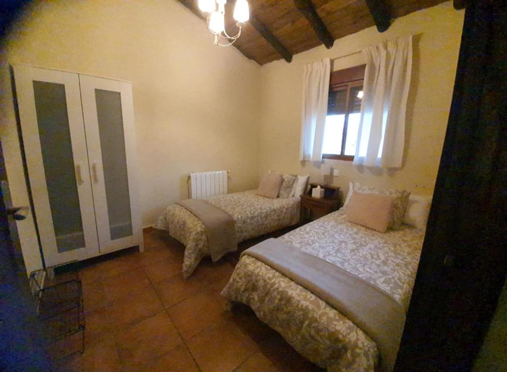 a bedroom with two beds and a window at casa Rural Las Traviesas in Candeleda