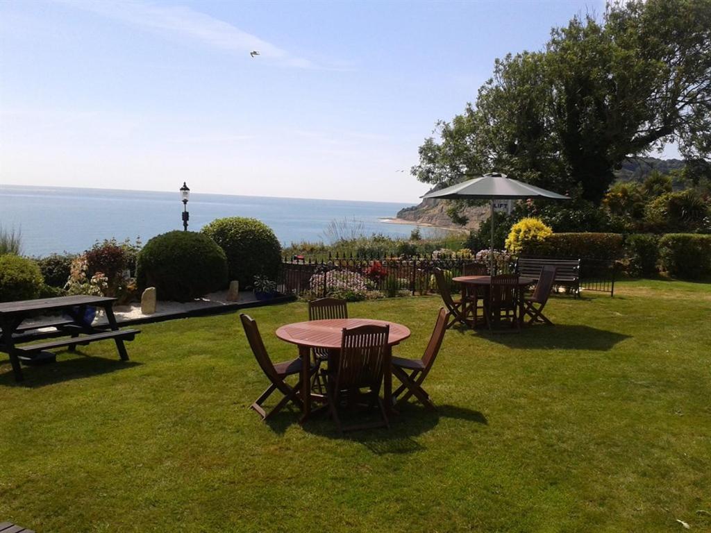 uma mesa e cadeiras num campo com o oceano em The Cliff Hall em Shanklin