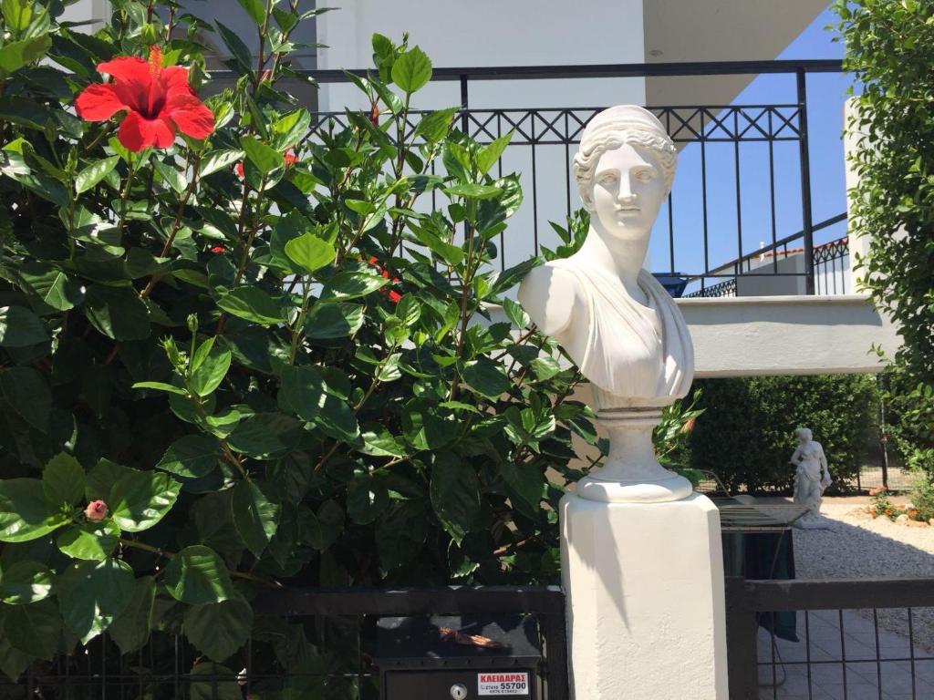 una estatua de un busto junto a una flor roja en Best location in Vrachati, en Vrachati