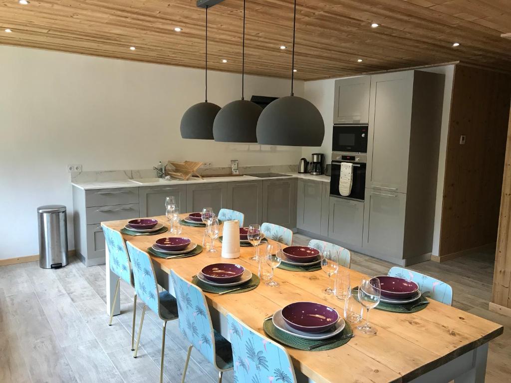 a kitchen with a wooden table and blue chairs at La Maison du Hérisson in Samoëns